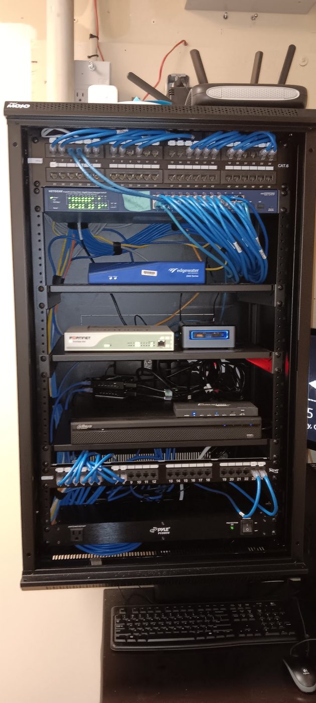 Open network rack showing Cat6 patch panels, switches, and cable management